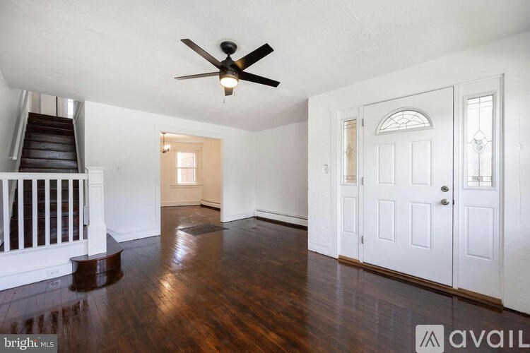 A spacious room with a ceiling fan and hardwood floors.