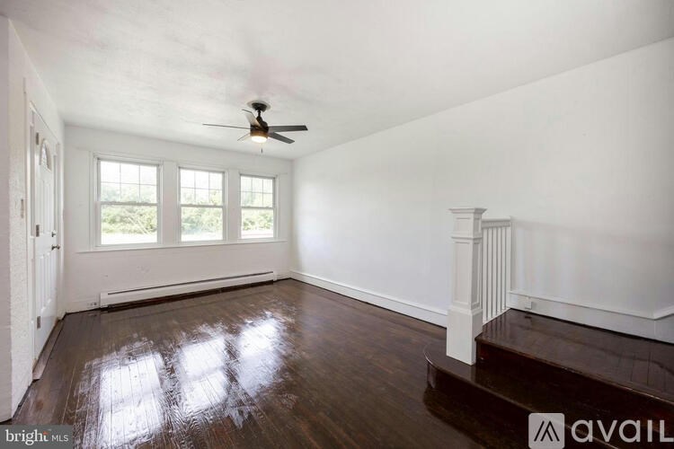 A room with a ceiling fan and wooden floors.