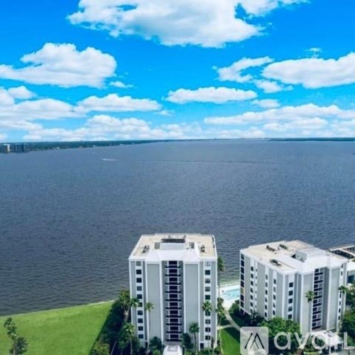Two white buildings are situated on a grassy area by the water.