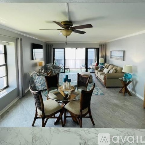 A dining room with a table set for six and a couch in the background.
