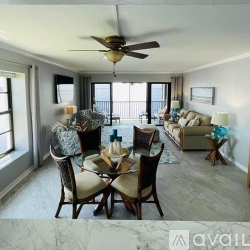 A dining room with a table set for six and a couch in the background.