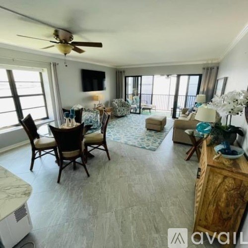A living room with a ceiling fan and a flat screen TV mounted on the wall.