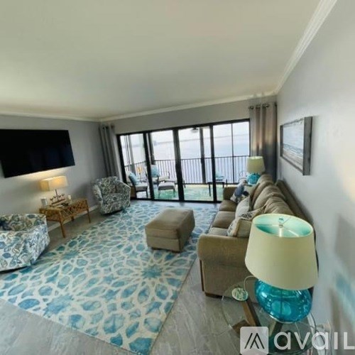 A living room with a blue patterned carpet and a flat screen TV mounted on the wall.