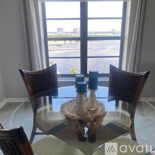 A table with two chairs and a vase on it in front of a window.