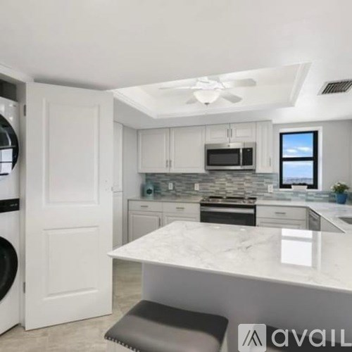 A modern kitchen with a white marble island and a ceiling fan.