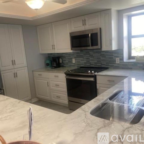 A kitchen with white cabinets and a black stove top oven.