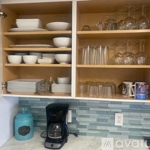 A kitchen cabinet with plates and glasses on the shelves.