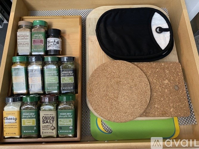 A drawer contains a variety of spices and a pair of cork coasters.
