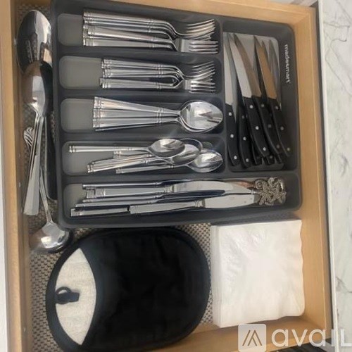 A set of silverware is neatly organized in a wooden box.