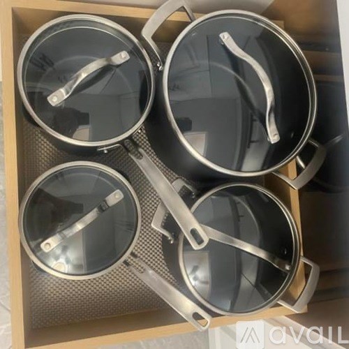 Four pots are stacked in a wooden box.