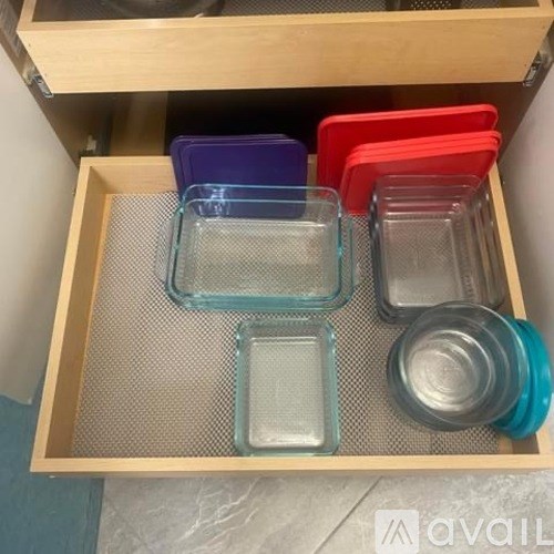 A drawer with a mesh bottom contains several square and rectangular containers.