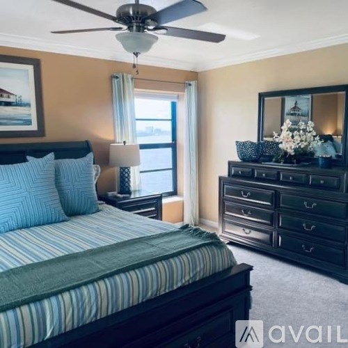 A bedroom with a bed, dresser, and a ceiling fan.