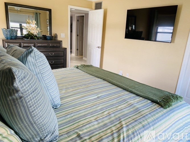 A bedroom with a bed, dresser, mirror, and window.
