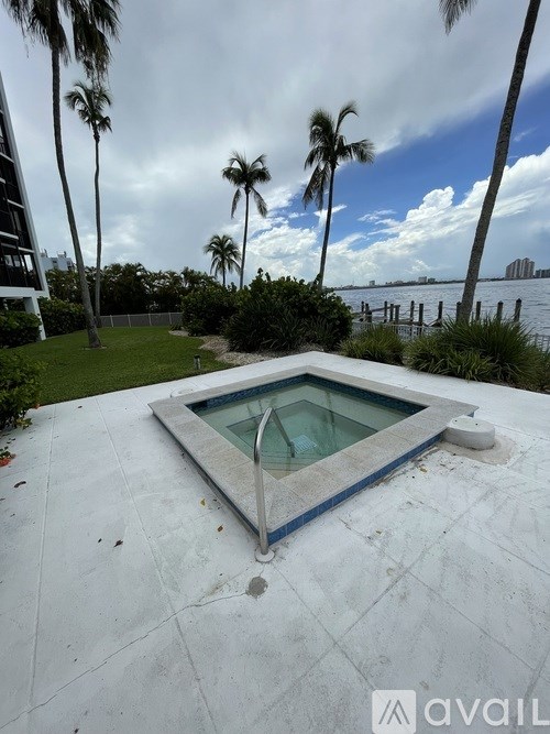 A pool surrounded by palm trees and a cloudy sky.