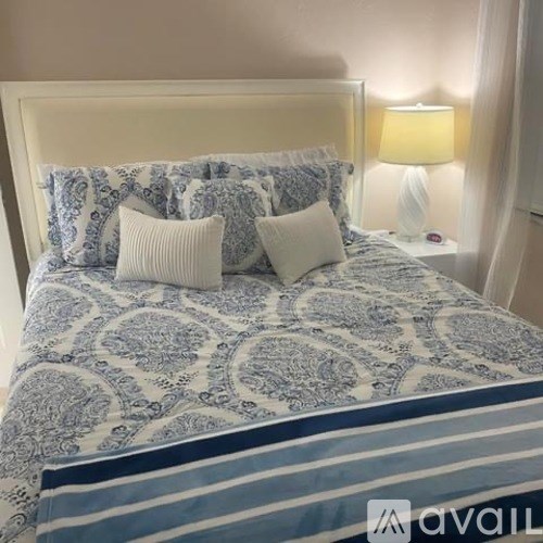 A bed with a blue and white patterned comforter and pillows.