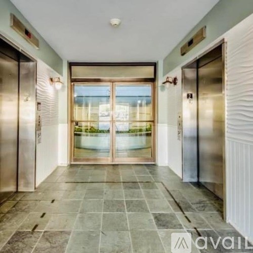 A hallway with two elevators on either side and a glass door in the middle.