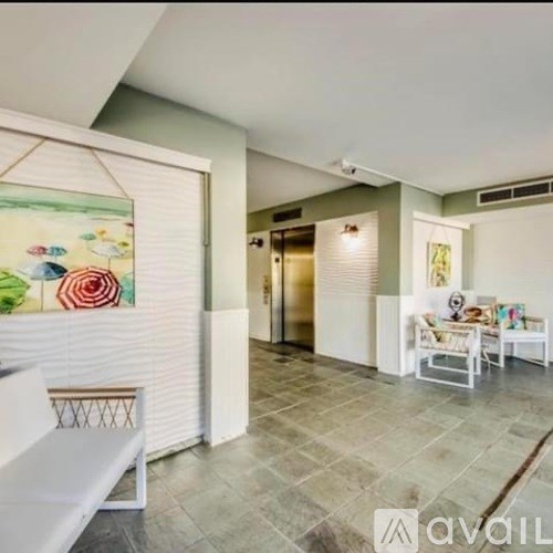 A living room with a white sofa and a painting on the wall.