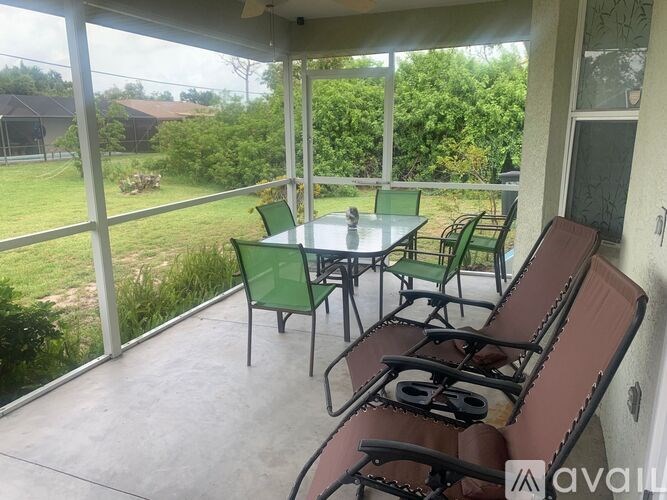 A patio with a table and chairs overlooking a green yard.