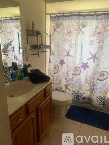 A bathroom with a shower curtain that has a pattern of stars and sea creatures.