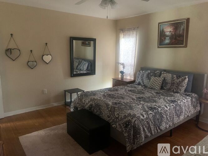 A bedroom with a bed, a mirror, and three heart-shaped items on the wall.