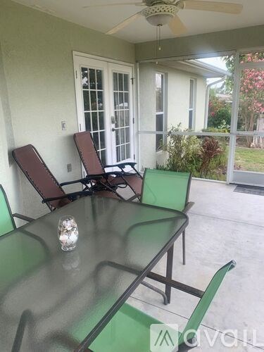 A glass table with two chairs and a ceiling fan.