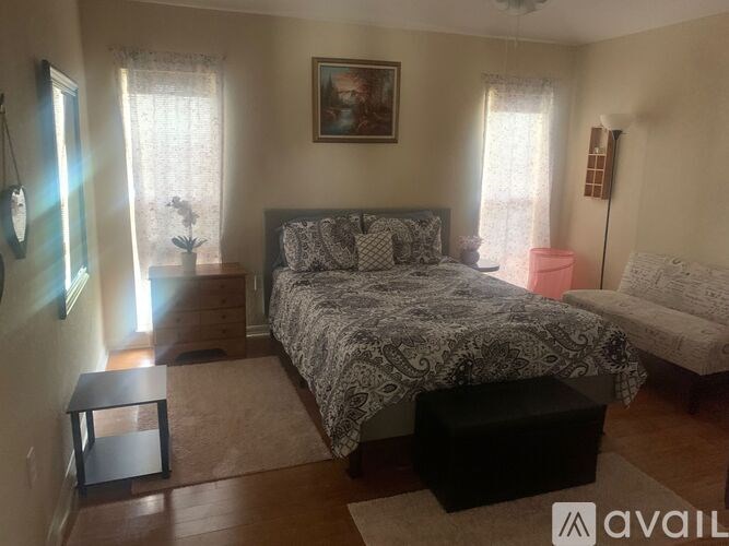 A bedroom with a bed, a chair, and a painting on the wall.