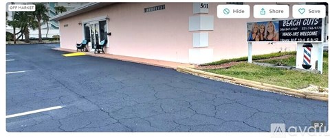 A pink building with a sign that says "BEACH CUTS" in front of it.