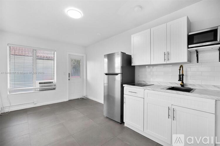 A kitchen with white cabinets and a stainless steel refrigerator.