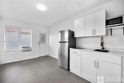 A kitchen with white cabinets and a stainless steel refrigerator.