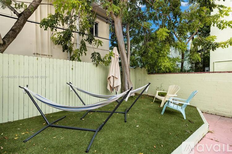 A hammock is hung between two trees in a backyard.