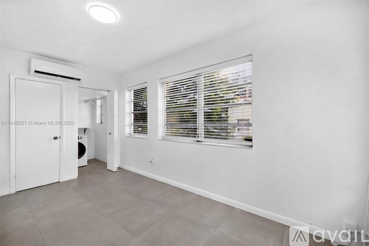 A spacious room with a door leading to a bathroom and a window with blinds.