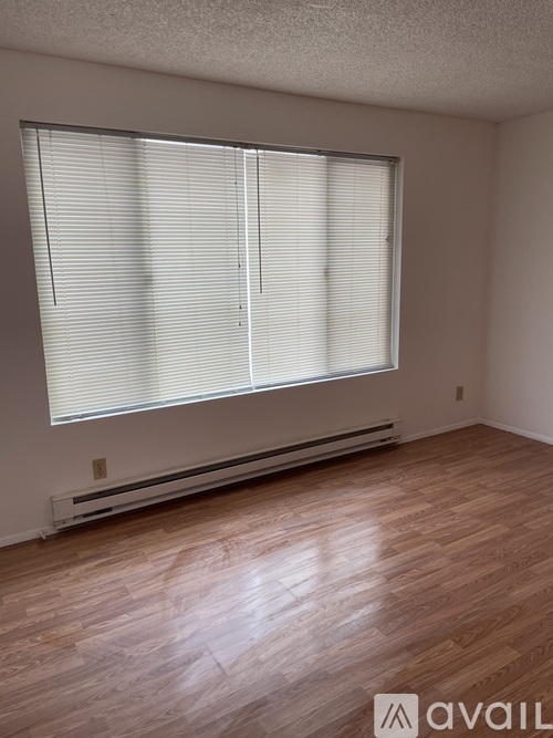 A room with wooden floors and a window with blinds.