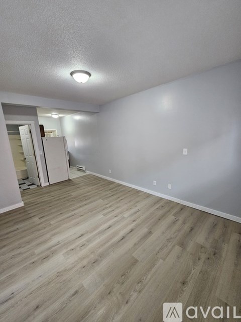 A room with wooden flooring and a white wall.