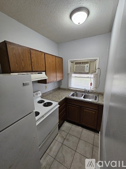 A kitchen with a stove, sink, and cabinets.