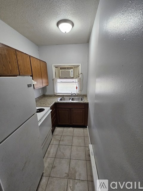 A kitchen with white appliances and brown cabinets.