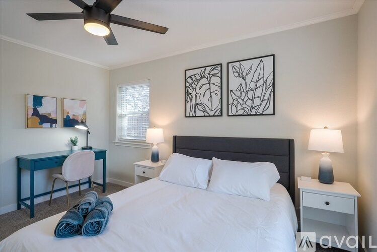 A bedroom with a bed, desk, chair, and two lamps.