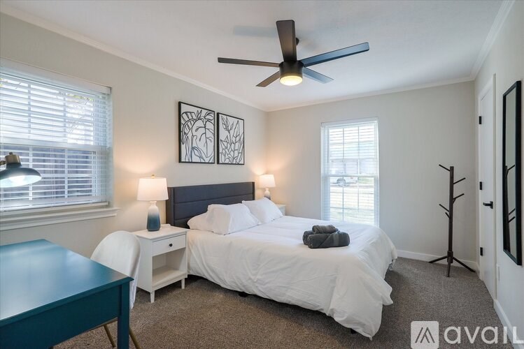 A bedroom with a large bed, a ceiling fan, and two lamps.