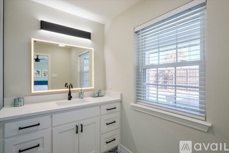A bathroom with a white vanity and a large mirror.