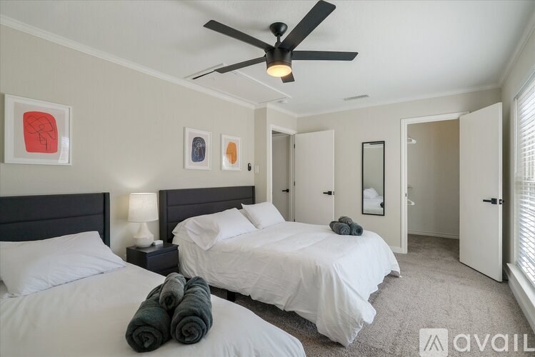 A bedroom with two beds and a ceiling fan.