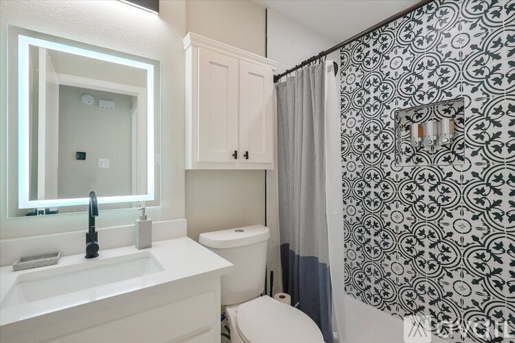A bathroom with a white sink, toilet, and shower curtain.