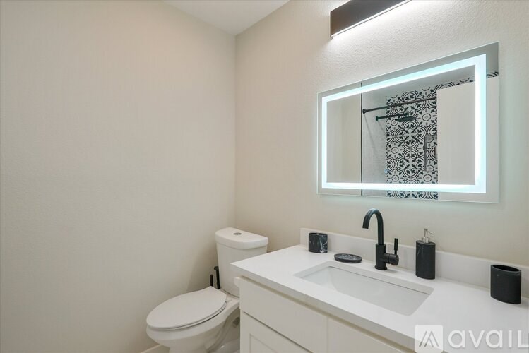 A white bathroom with a toilet, sink, and mirror.