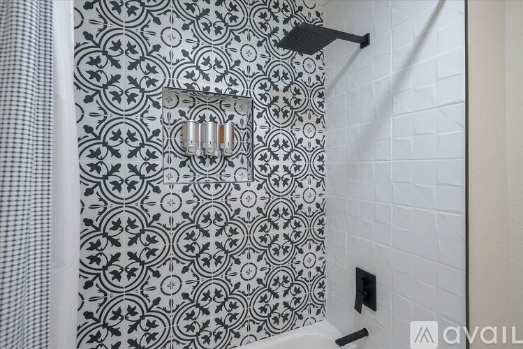A shower area with a black and white tiled wall.