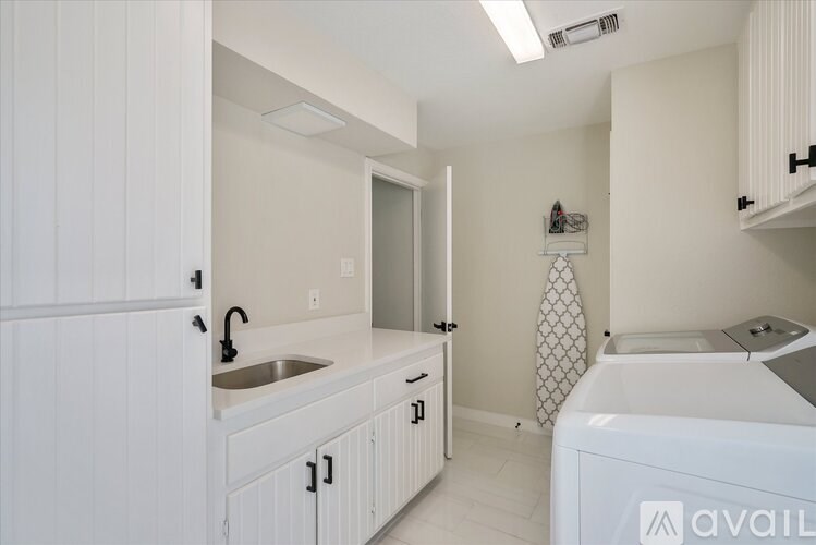 A white bathroom with a sink, mirror, and bathtub.