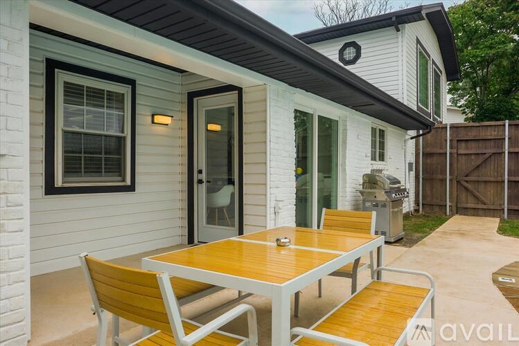 A white house with a wooden table and chairs outside.