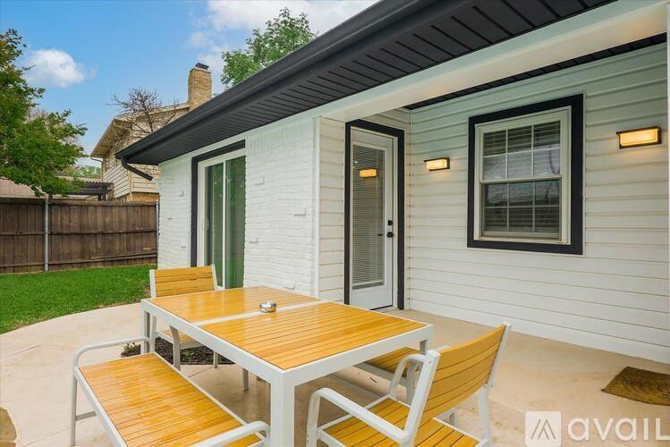 A small white house with a wooden table and chairs in front.