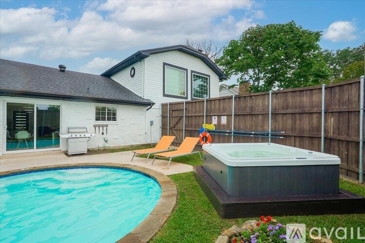 A pool and hot tub area in front of a house.