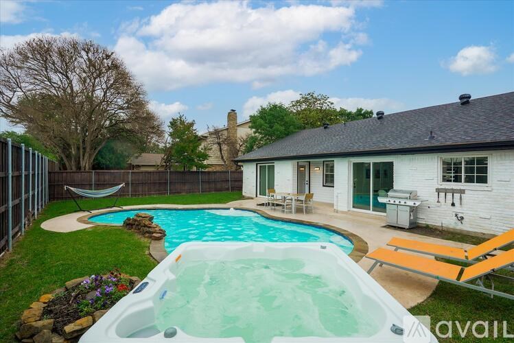 A hot tub is in the foreground of a backyard with a hammock and a house in the background.