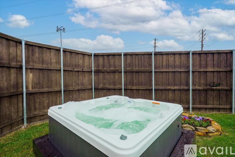 A hot tub sits in a backyard surrounded by a wooden fence.