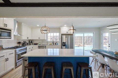 A kitchen with white cabinets and a blue backsplash.