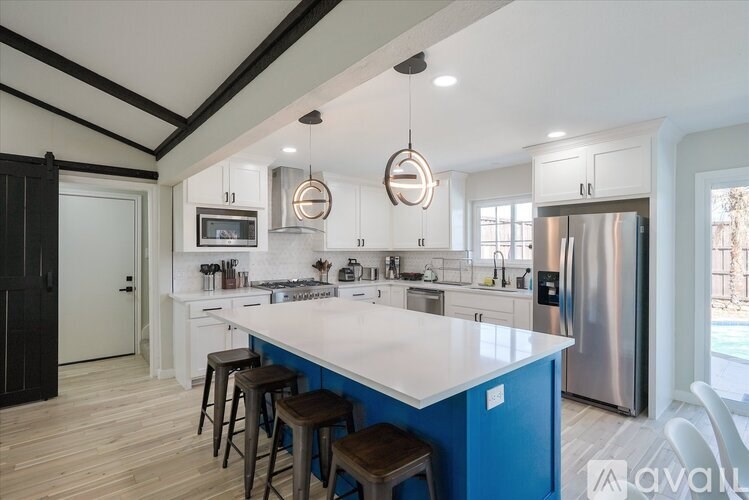 A modern kitchen with a blue island and stools.